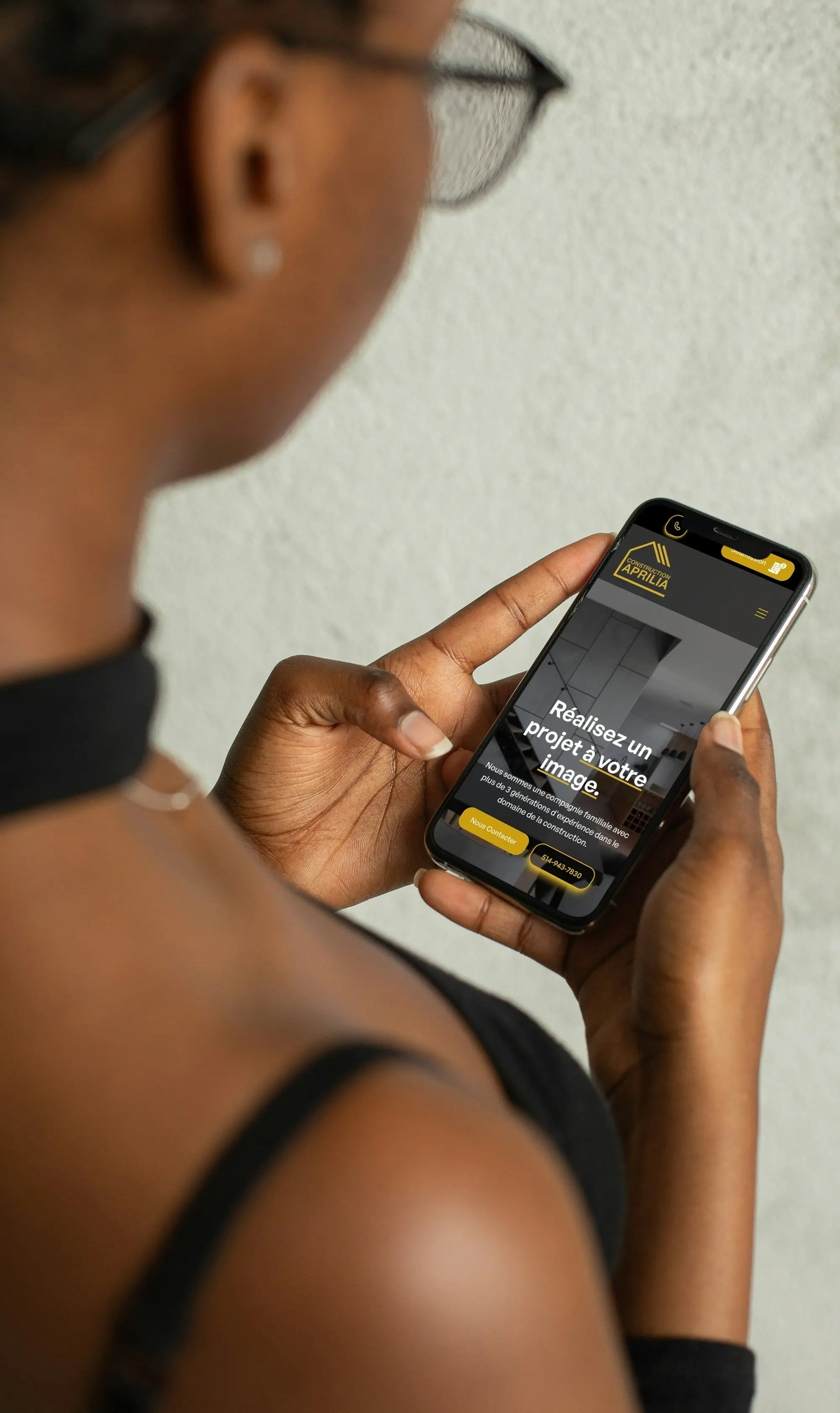black woman, using her phone to look at the mobile responsive website created by April Web Solutions, for the construction company Construction Aprillia.